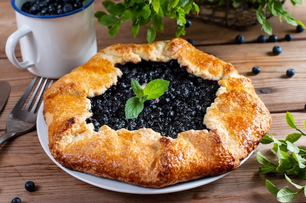 Pie with fresh and cooked blueberries on wooden table