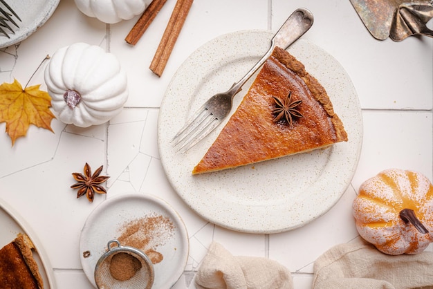 Piece of american pumpkin pie with cinnamon on white tile background top view