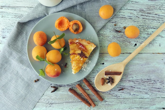 A piece of apricot pie on a plate, sprinkled with powdered sugar, spices and apricots