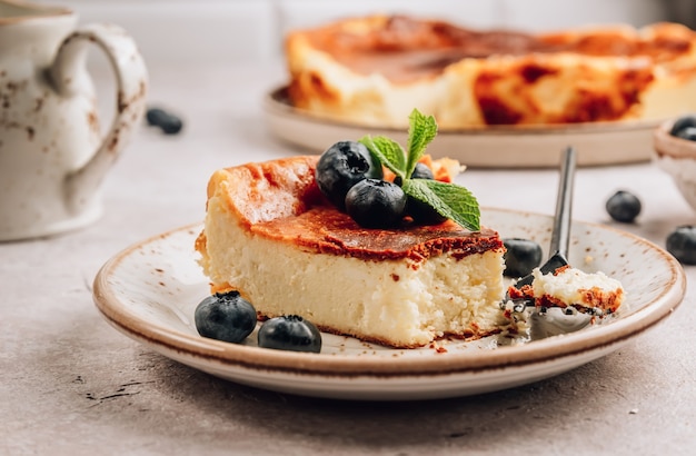 Photo a piece of basque burnt cheesecake put, the whole cake is at the background. tarta de queso.