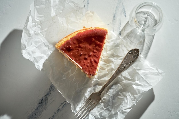 A piece of Basque cheesecake on parchment with a fork Sunlight in the morning Minimalist concept with space for text