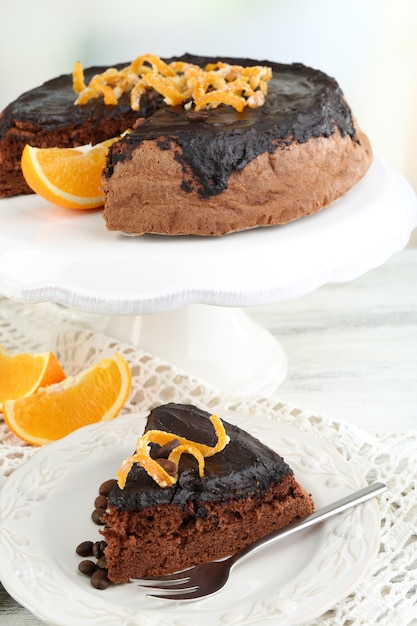 Piece of Cake with Chocolate Glaze and orange on plate, on wooden table