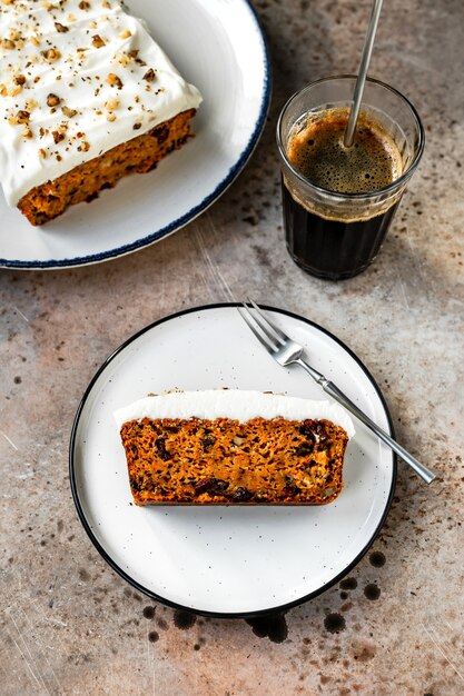 Photo a piece of a carrot cake with cranberries, walnuts and cream cheese frosting, on a white plate.