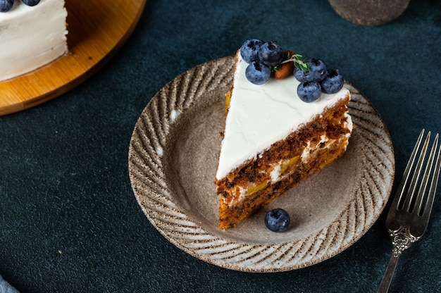 Piece of carrot cake with walnuts and blueberry on dark wood background. Local food. Traditional american cake. Cake for thanksgiving day. Christmas cake.