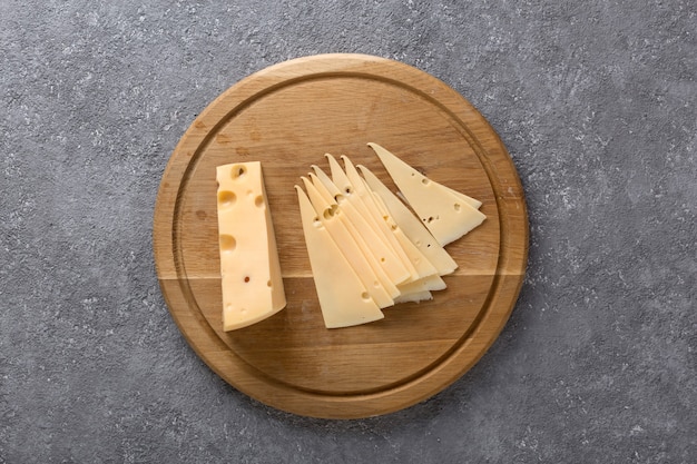 piece of cheese and slices on a kitchen board close up