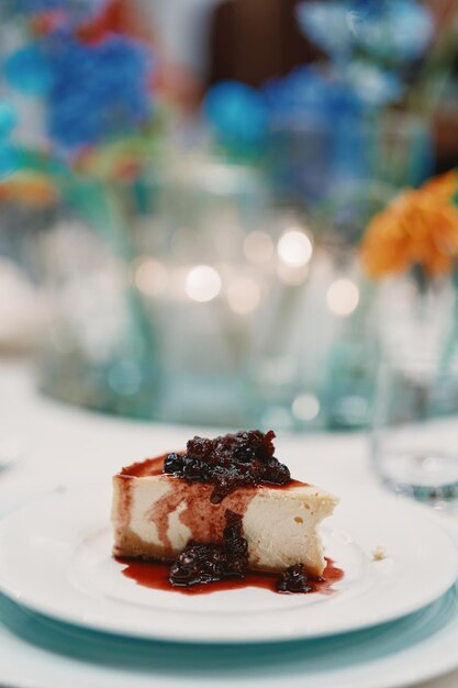 Piece of cheesecake covered with jam lies on a plate on the table