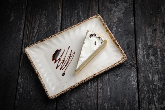 piece of cheesecake with cream and chocolate on a white plate