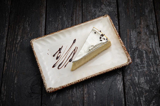 piece of cheesecake with cream and chocolate on a white plate