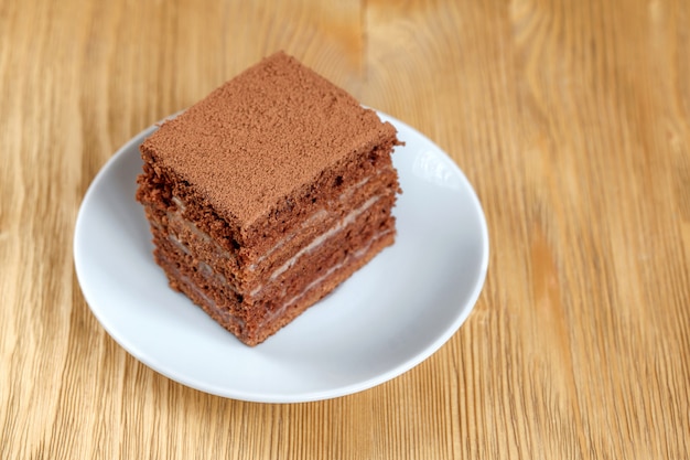 Piece of chocolate cake in white plate on wooden table