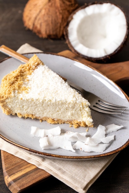 Piece of coconut cheesecake on a plate with fresh coconut