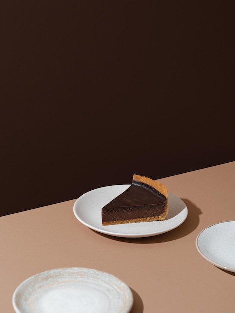 Piece of dark chocolate cheesecake on beige and brown background, minimalist food photography