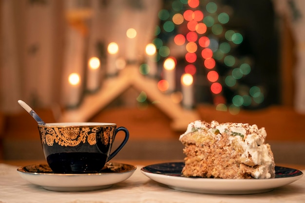 A piece of delicious cake decorated with cream and banana slices and a cup of tea