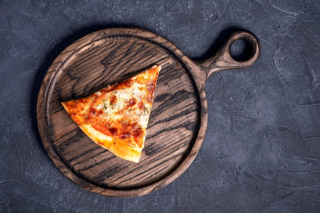 A piece of delicious hot pizza on a wooden oak board Top view Copy space