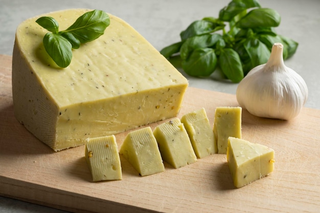 Piece of Dutch organic cheese with garlic and basil leaves