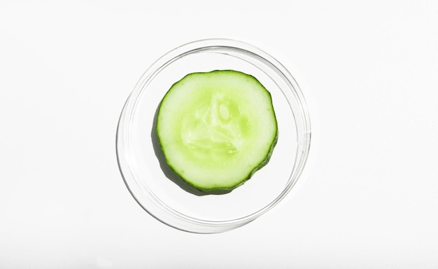 A piece of fresh green juicy cucumber in a glass container on a white background