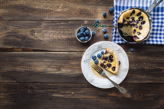 Piece of fresh homemade Dutch Baby pancake with blueberries on rustic wooden background