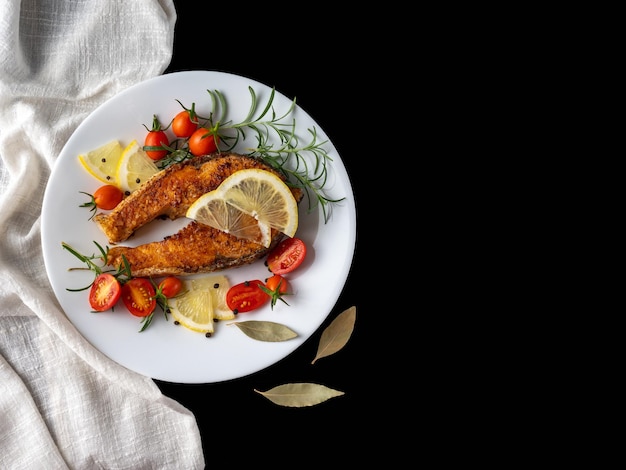 A piece of fried fish with vegetables on a white plate.