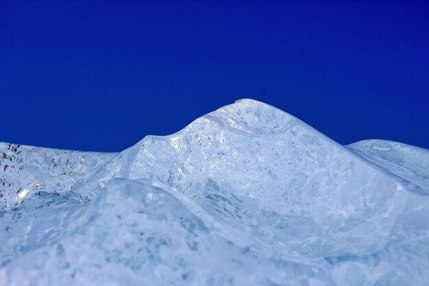 A piece of ice in the form of mountains on a blue background macro