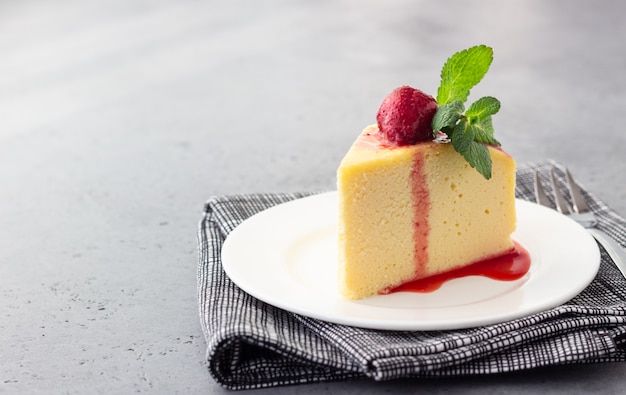 A piece of Japanese cotton cheesecake with mint and strawberry.