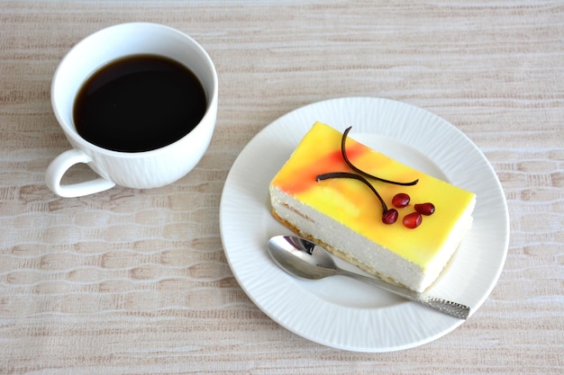 piece of lemon cake on white saucer decorated with pomegranate seeds, close-up