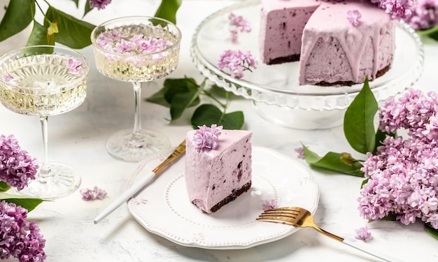 A piece of mousse cake Delicious dessert blueberry tart with fresh berries with a bouquet of purple blooming lilacs vertical image place for text