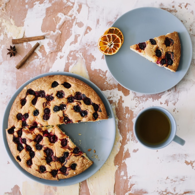 Piece of pie on plate with cup of tea on white table