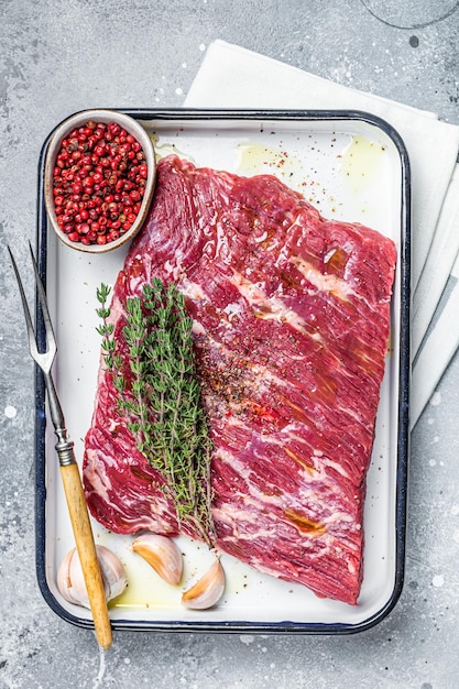 Piece of raw beef brisket with herbs and spices ready for bbq smoker Gray background Top view