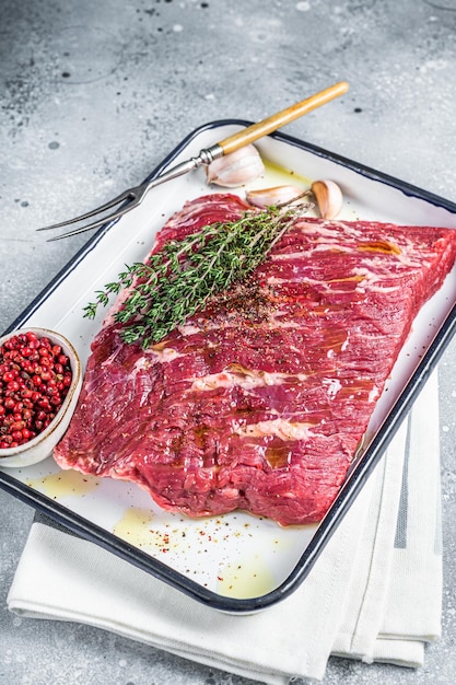 Piece of raw beef brisket with herbs and spices ready for bbq smoker Gray background Top view