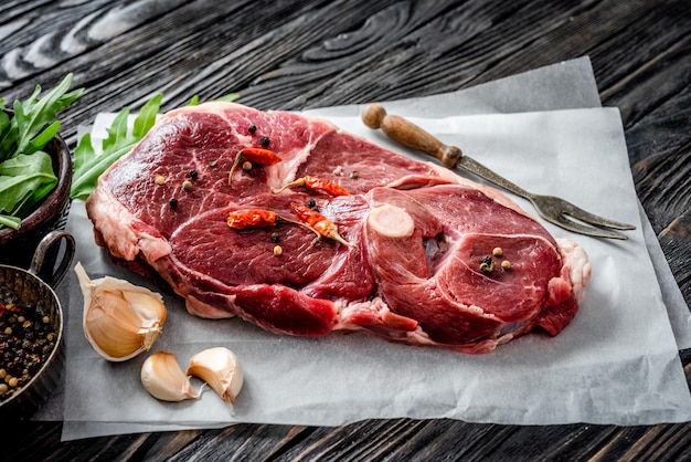 Piece of raw lamb meat with spices on dark wooden table