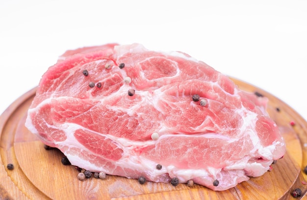 A piece of raw pork meat on a white background on a wooden board