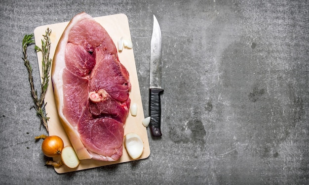 A piece of raw pork with spices and a cutting knife