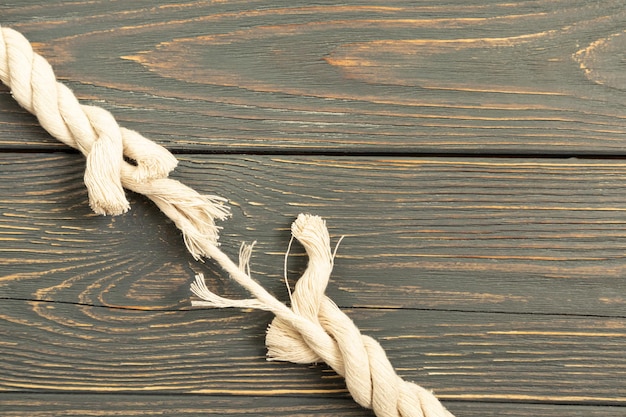 A piece of rope that is about to break on a gray wooden background Gap