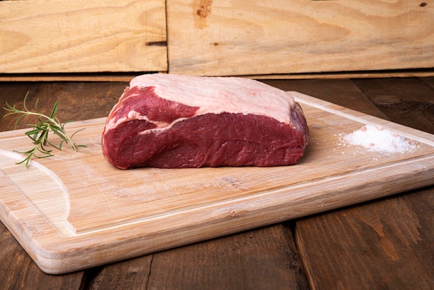 Piece of sirloin rosemary and salt on bamboo cutting board