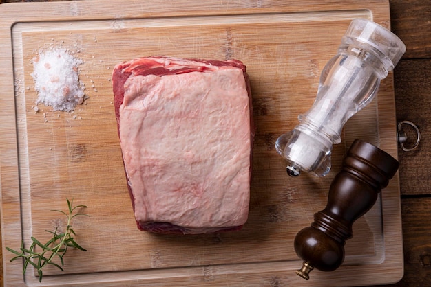 Piece of sirloin rosemary salt and pepper moulin on bamboo cutting board