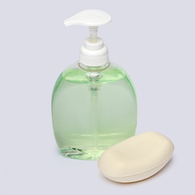 piece of soap and bottle of liquid soap over light grey backgound with clipping path