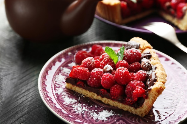 Piece of tart with fresh raspberries on wooden background