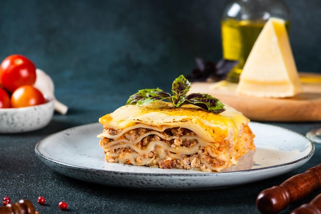 Piece of tasty hot lasagna on dark background. Traditional italian lasagna. Italian food. Close up lasagna. Bolognese sauce. Bechamel sauce. Still life of food. Homemade meat lasagna.