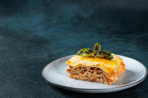 Piece of tasty hot lasagna on dark background Traditional italian lasagna Italian food Close up lasagna Bolognese sauce Bechamel sauce Still life of food Homemade meat lasagna