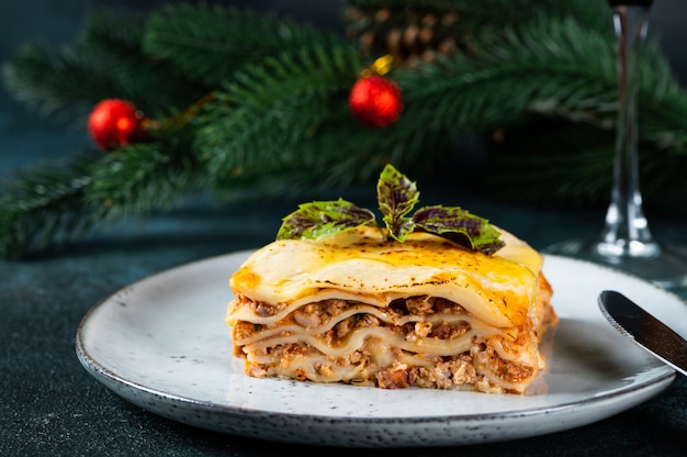 Piece of tasty hot lasagna on light background. Traditional italian lasagna. Italian food. Close up lasagna. Lasagna with christmas decor. Still life of food. Homemade pasta