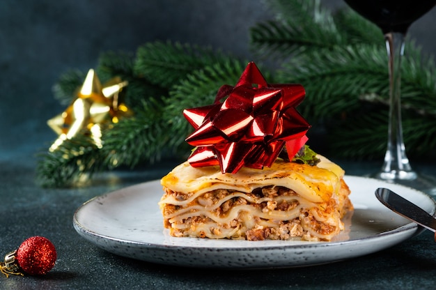 Piece of tasty hot lasagna on light background. Traditional italian lasagna. Italian food. Close up lasagna. Lasagna with christmas decor. Still life of food. Homemade pasta