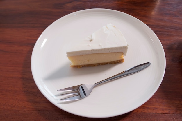 A piece of white cake and fork on white plate.