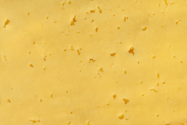 Photo a piece of yellow cheese with holes close-up.