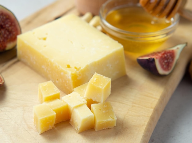 Pieces of aged cheese, nuts, figs and honey on a cutting board,