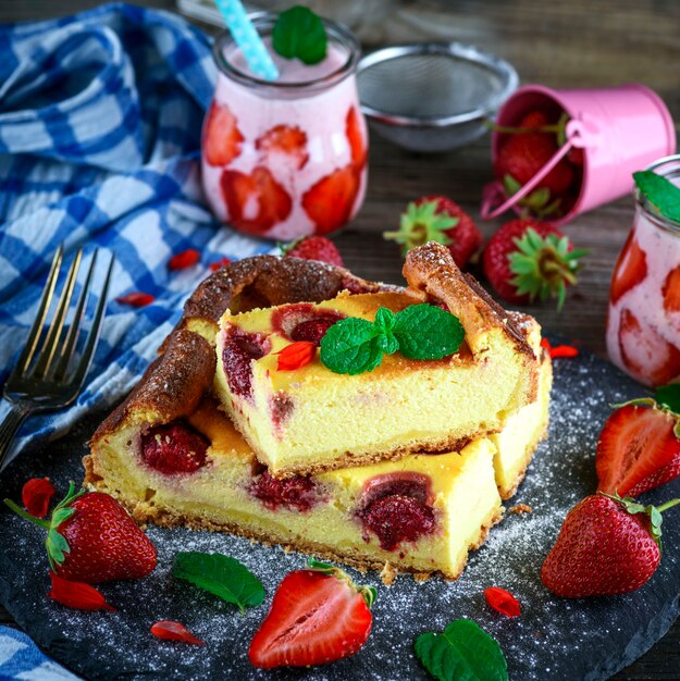 Pieces of cheesecake with strawberries on a black graphite plate