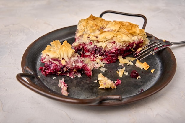 Pieces of cherry pie from filo dough and fork on rustic metal tray close up selective focus