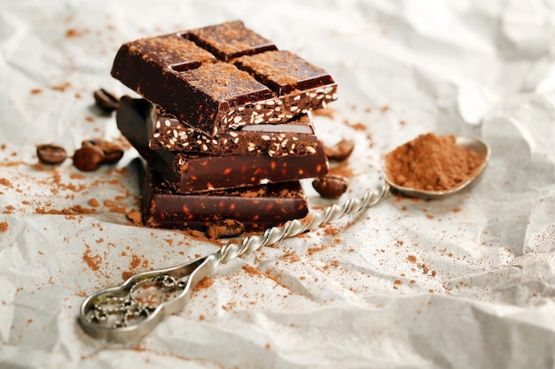 Pieces of chocolate with cocoa on parchment closeup