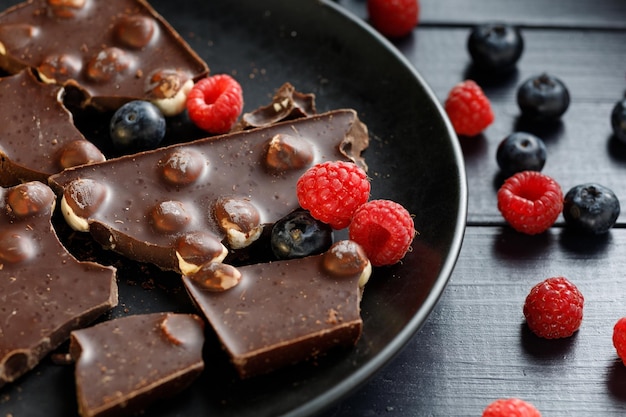 Pieces of chocolate with nuts and berries in a black plate