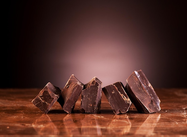 Pieces dark chocolate on a marble brown background