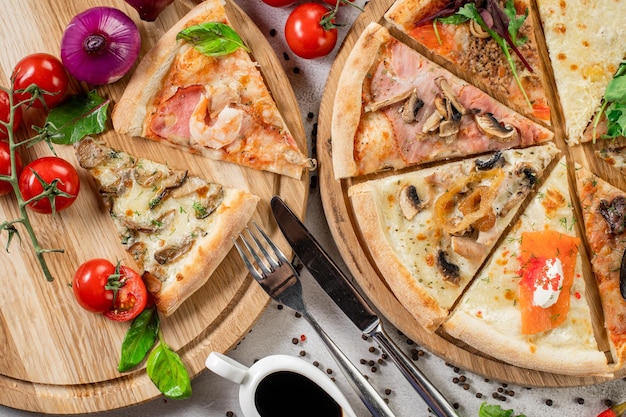 Pieces of different pizza flat lay on concrete background