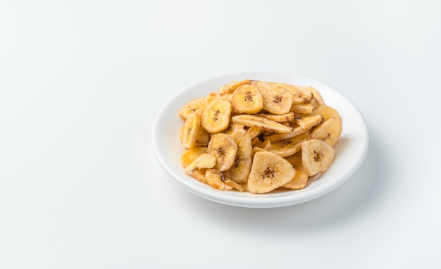 Pieces of dried bananas in a white plate on a light background